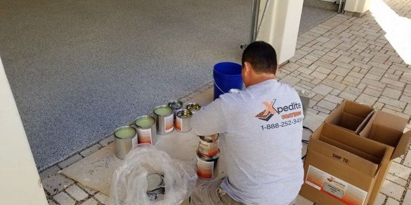 Xpedite Coatings technician applying epoxy topcoat to residential garage in Houston, TX.